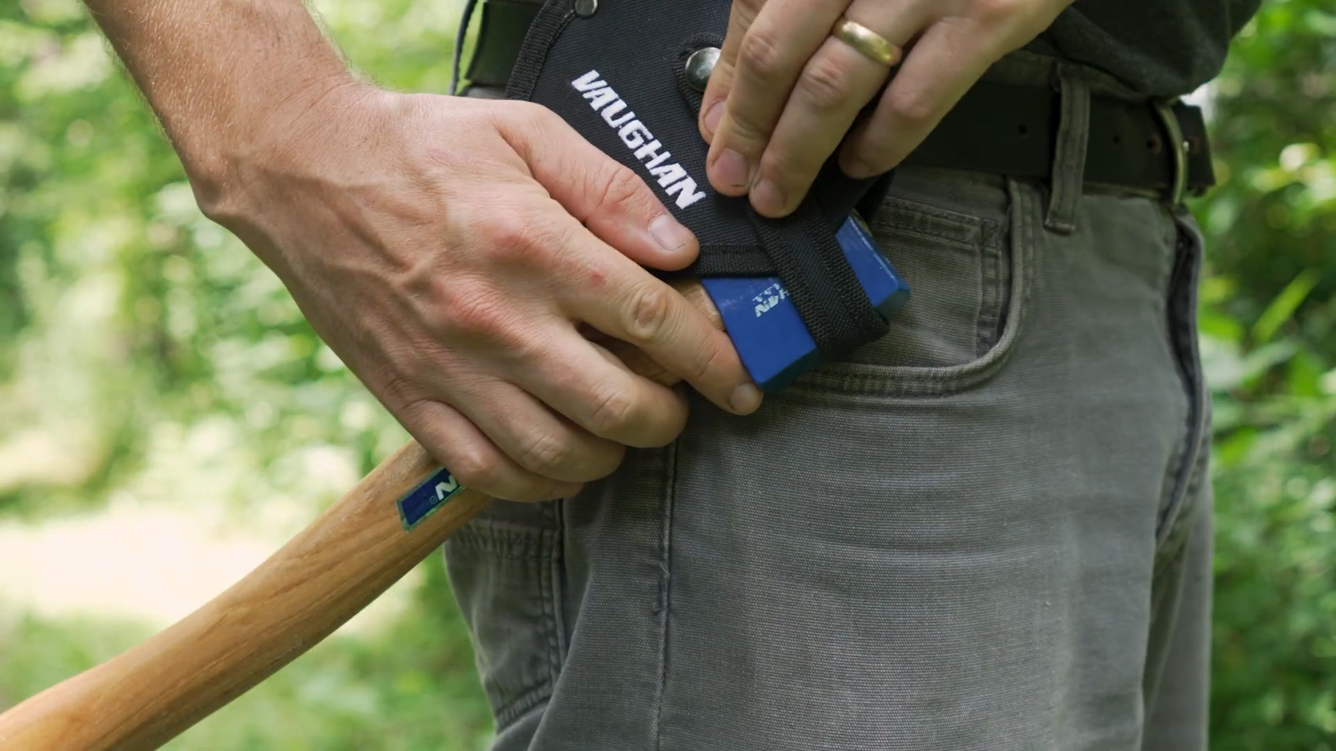 man securing camp axe with the sheath to his belt